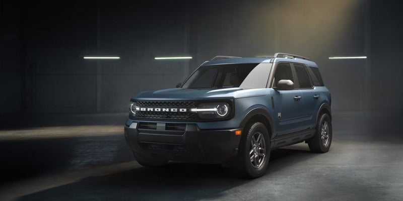 Blue Ford Bronco Sport SUV parked in a dark garage with linear ceiling lights.