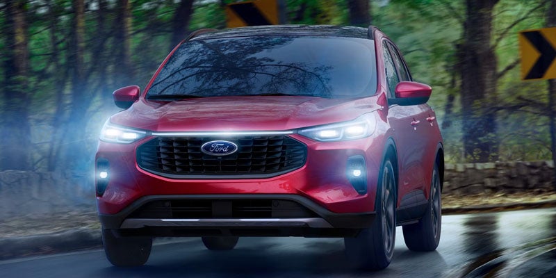 Red Ford SUV with bright headlights driving on a wet road