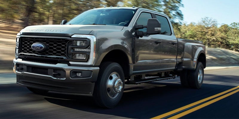 Gray Ford Super Duty dually truck driving on a paved road 