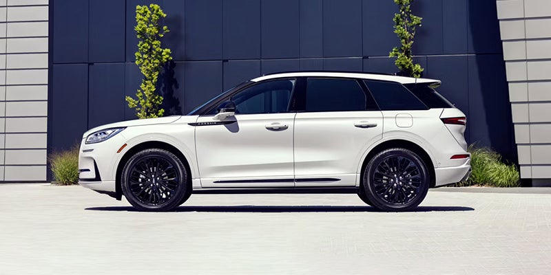 White luxury SUV parked in front of a modern building with black wheels and tinted window